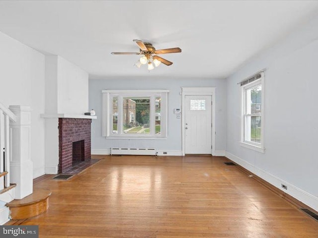 unfurnished living room featuring ceiling fan, a baseboard radiator, light hardwood / wood-style flooring, and a brick fireplace