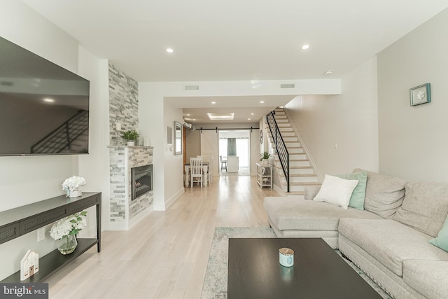 living room featuring light hardwood / wood-style floors, a fireplace, and a barn door