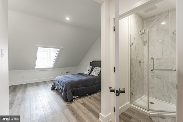 bedroom with vaulted ceiling with skylight and hardwood / wood-style flooring