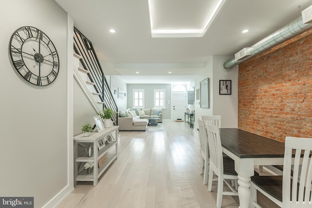 dining room with light hardwood / wood-style flooring and brick wall