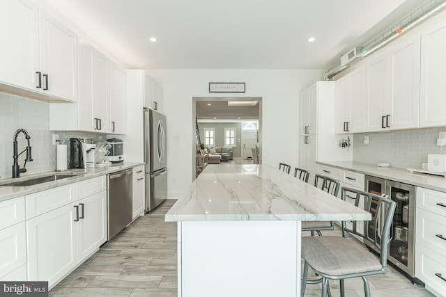 kitchen with light wood-type flooring, a center island, sink, a kitchen bar, and appliances with stainless steel finishes