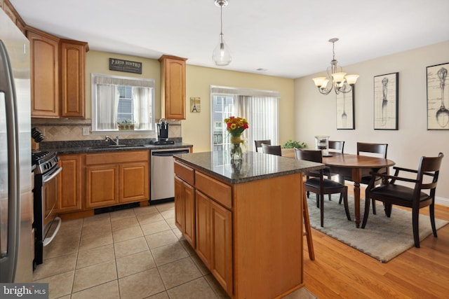 kitchen featuring pendant lighting, a wealth of natural light, a kitchen island, and stainless steel appliances