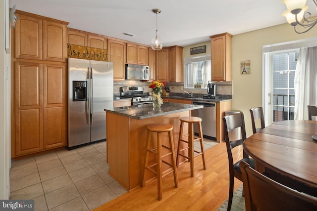 kitchen with appliances with stainless steel finishes, tasteful backsplash, a healthy amount of sunlight, and a kitchen island