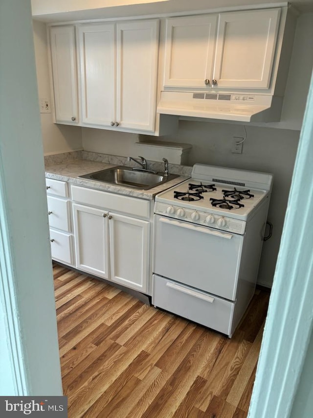 kitchen featuring sink, extractor fan, white cabinetry, light wood-type flooring, and white range with gas cooktop