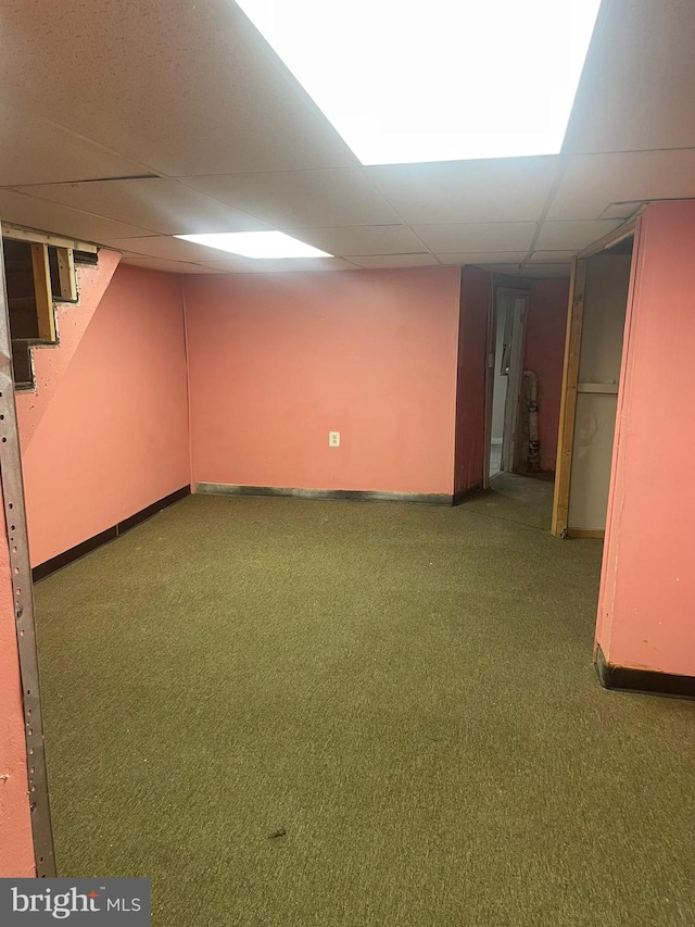 basement with a drop ceiling and dark carpet