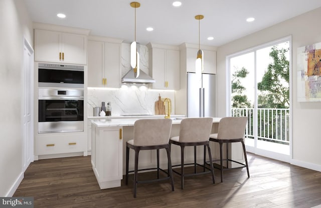 kitchen with stainless steel appliances, white cabinetry, a center island with sink, and wall chimney range hood