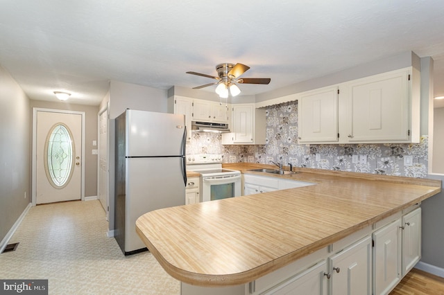 kitchen with kitchen peninsula, sink, electric stove, white cabinetry, and stainless steel refrigerator