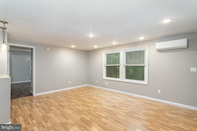 empty room featuring a wall mounted air conditioner and light hardwood / wood-style flooring