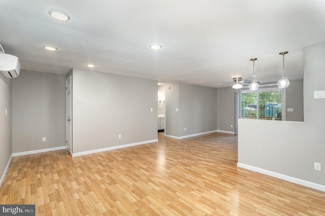 unfurnished room with an AC wall unit, light wood-type flooring, and ceiling fan