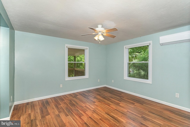 spare room featuring hardwood / wood-style floors, a wall mounted AC, and a healthy amount of sunlight