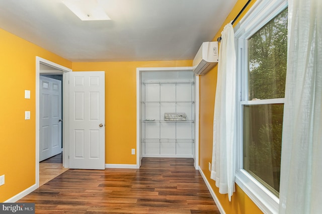 unfurnished bedroom featuring a wall mounted AC and dark hardwood / wood-style floors