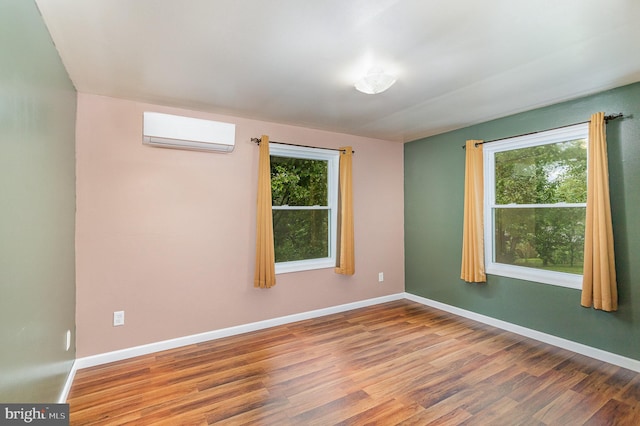 spare room featuring a wall mounted air conditioner and hardwood / wood-style floors