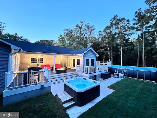 back house at dusk with a yard, an outdoor living space, and a wooden deck