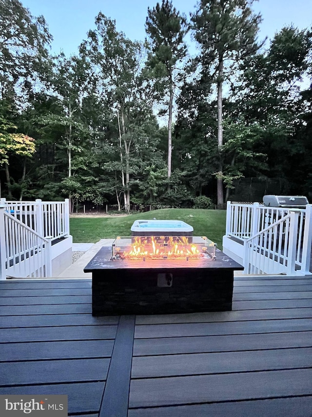 wooden deck with a lawn and an outdoor fire pit