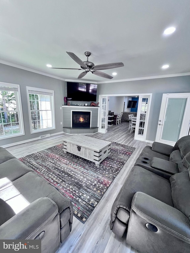 living room with crown molding, ceiling fan, and light hardwood / wood-style flooring