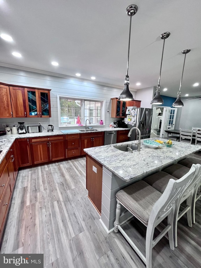 kitchen with pendant lighting, light stone counters, sink, a kitchen breakfast bar, and light hardwood / wood-style flooring