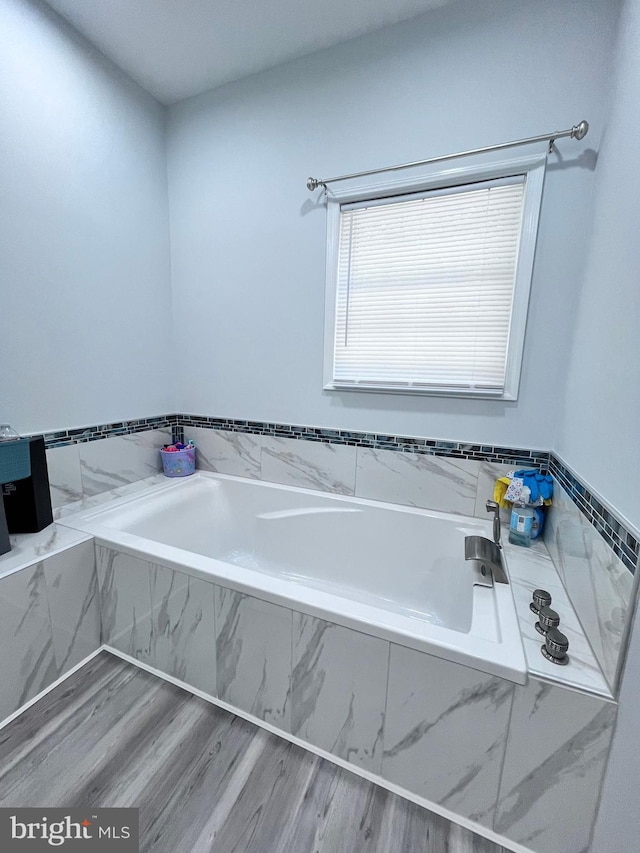 bathroom with wood-type flooring and a relaxing tiled tub