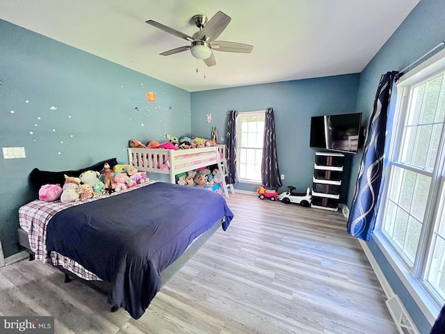 bedroom featuring wood-type flooring, multiple windows, and ceiling fan