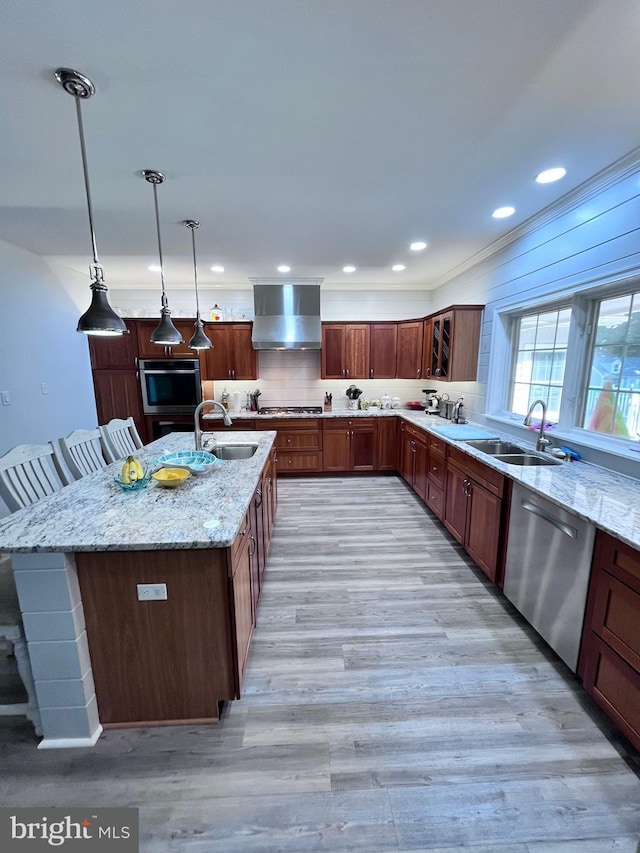 kitchen featuring appliances with stainless steel finishes, wall chimney exhaust hood, sink, and pendant lighting