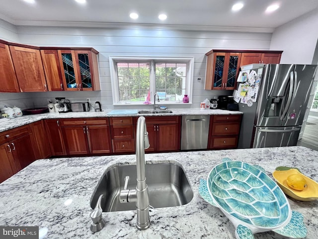 kitchen with appliances with stainless steel finishes, backsplash, sink, and light stone counters