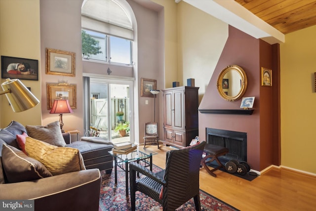 sitting room featuring wood ceiling, a towering ceiling, and hardwood / wood-style flooring