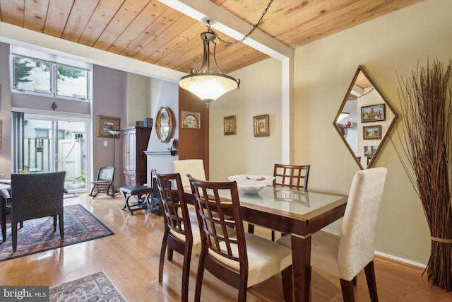 dining space featuring wooden ceiling, light hardwood / wood-style floors, and a high ceiling