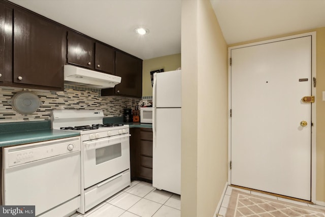 kitchen featuring dark brown cabinets, light tile patterned floors, tasteful backsplash, and white appliances