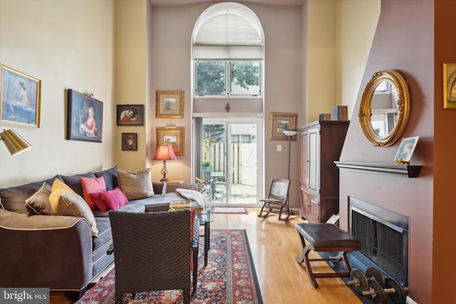 living room featuring light wood-type flooring and a towering ceiling