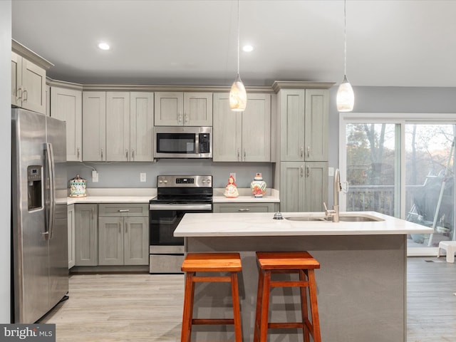 kitchen featuring stainless steel appliances, sink, pendant lighting, gray cabinets, and light hardwood / wood-style floors