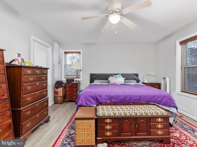 bedroom with ceiling fan, multiple windows, and light hardwood / wood-style flooring