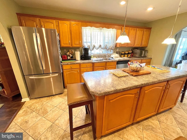 kitchen featuring a kitchen bar, stainless steel appliances, sink, and a healthy amount of sunlight