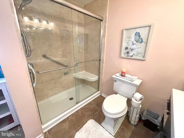 bathroom featuring vanity, toilet, a shower with door, and tile patterned floors