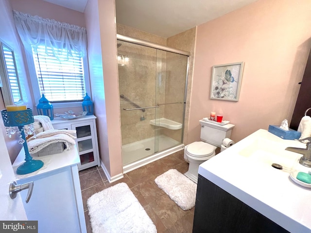 bathroom featuring vanity, a shower with shower door, toilet, and tile patterned flooring