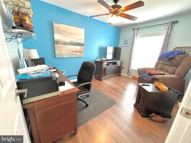 home office with light wood-type flooring and ceiling fan