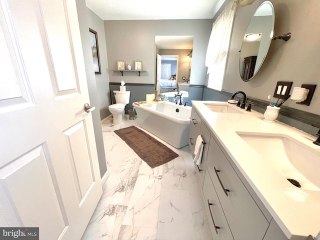 bathroom with a tub, vanity, a healthy amount of sunlight, and toilet