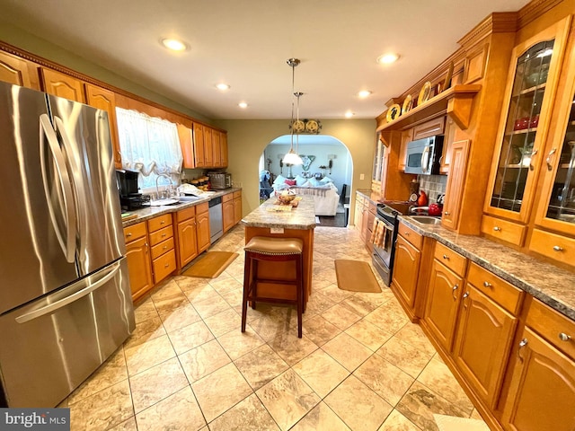 kitchen featuring a kitchen island, sink, hanging light fixtures, appliances with stainless steel finishes, and a kitchen bar