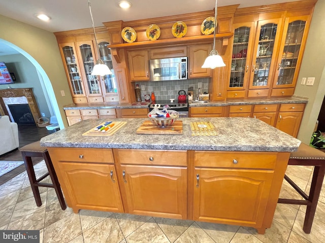 kitchen featuring pendant lighting, appliances with stainless steel finishes, a kitchen island, and a breakfast bar