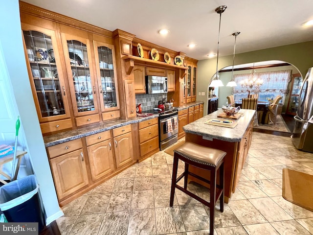 kitchen featuring a center island, stainless steel appliances, tasteful backsplash, an inviting chandelier, and decorative light fixtures