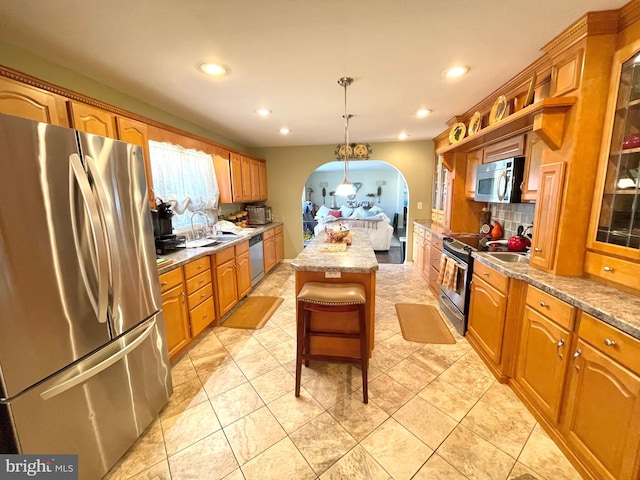 kitchen with backsplash, a kitchen breakfast bar, hanging light fixtures, appliances with stainless steel finishes, and a center island