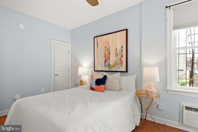 bedroom with wood-type flooring, ceiling fan, and a wall mounted air conditioner