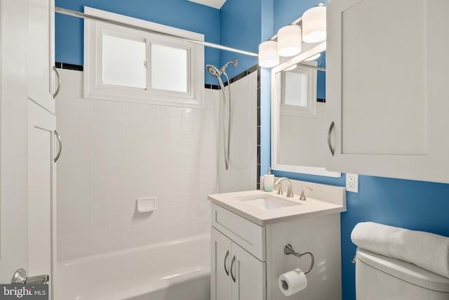 full bathroom with tiled shower / bath, vanity, and toilet