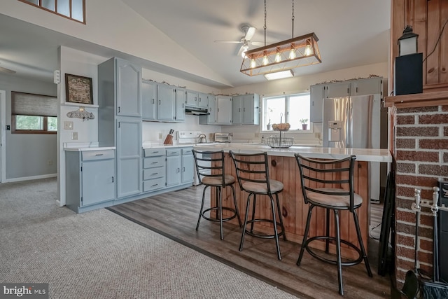 kitchen featuring ceiling fan, a kitchen island, hardwood / wood-style flooring, white stove, and vaulted ceiling