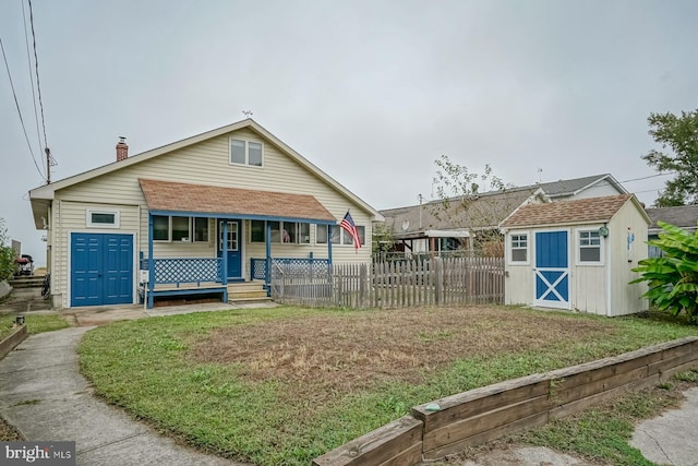 view of front facade featuring a front lawn, covered porch, and a shed