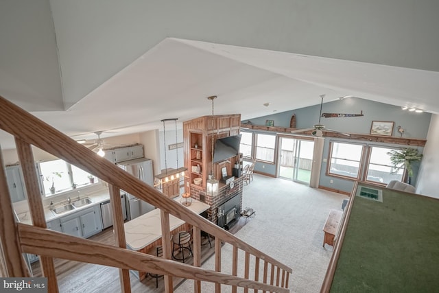 stairway featuring ceiling fan, lofted ceiling, sink, carpet floors, and a fireplace