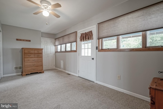 interior space with a healthy amount of sunlight, light carpet, and ceiling fan