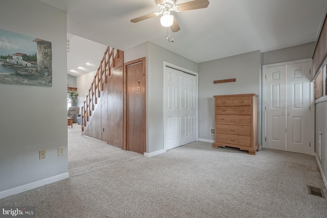 interior space featuring light carpet, two closets, and ceiling fan