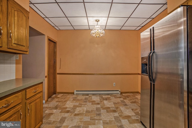 kitchen featuring stainless steel fridge with ice dispenser, a drop ceiling, hanging light fixtures, and a baseboard heating unit