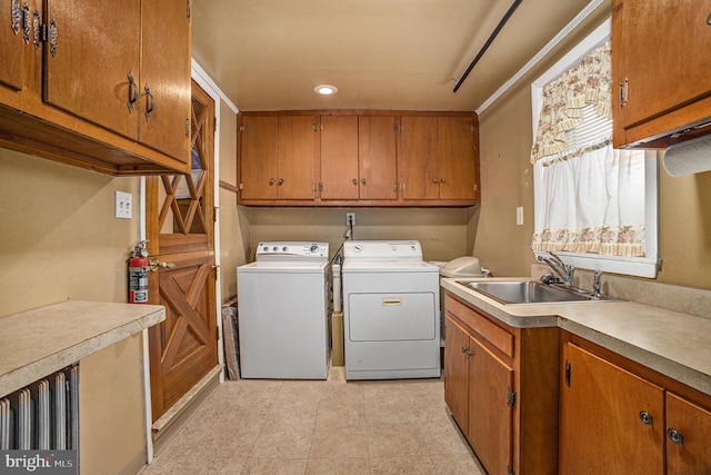 laundry area featuring washing machine and clothes dryer, crown molding, cabinets, and sink