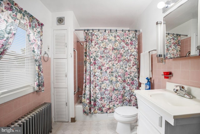 full bathroom featuring radiator heating unit, tile walls, toilet, vanity, and shower / tub combo