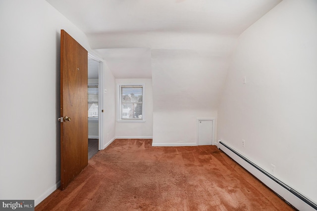 spare room with carpet, vaulted ceiling, and a baseboard heating unit